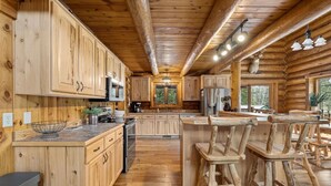 Una cocina de estilo rústico tipo cabaña, con armarios de madera, una isla central y una zona de bar con taburetes.