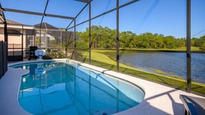 Piscina con vista a un lago y árboles, rodeada por una cerca de metal.