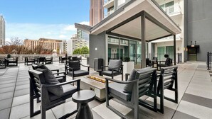 An outdoor seating area with modern furniture, a fire pit, and a view of a tall building in the background. - Stylish 2B2B Apartment in Downtown ATL (Atlanta)