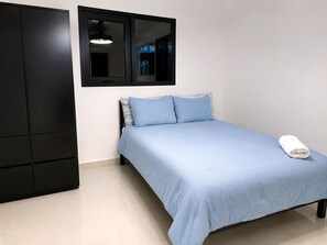 A bedroom with a bed, a wardrobe, and a window with a hanging light fixture.