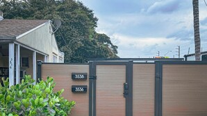 A gated entrance with two wooden doors marked with numbers 3536 and 3538, a gravel driveway, and a small patch of greenery. - Casa Kiwi in Miami - Sleeps 6 (Miami)