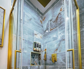 A bathroom with marble tiles, a shower with a gold faucet, and a hexagonal window. - Casa Kiwi in Miami - Sleeps 6 (Miami)