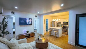 A modern living room with a sofa, a coffee table, and a TV mounted on the wall. - Casa Kiwi in Miami - Sleeps 6 (Miami)