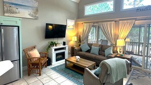 A living room with a television, sofa, coffee table, and a dining area with a table and chairs. - Private Beach House, Pet Friendly, Ft Morgan Sleeps 10, next to Kiva Golf Course (Gulf Shores)