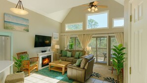 A spacious living room with a fireplace, comfortable seating, and large windows offering views of the outdoors. - Private Beach House, Pet Friendly, Ft Morgan Sleeps 10, next to Kiva Golf Course (Gulf Shores)