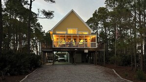 A two-story building with a balcony, a covered entrance, and a gravel driveway. - Private Beach House, Pet Friendly, Ft Morgan Sleeps 10, next to Kiva Golf Course (Gulf Shores)