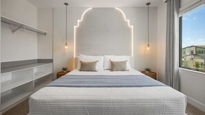 A modern bedroom with a large bed, bedside tables, a built-in shelf, and a view of buildings through the window. - 15 BD/ 16.5 BA/ Paradiso Grande (11078 MB) (Orlando)