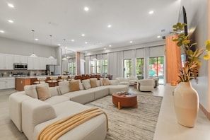 A modern living room with a sectional sofa, a coffee table, and a TV mounted on the wall. - 15 BD/ 16.5 BA/ Paradiso Grande (11078 MB) (Orlando)