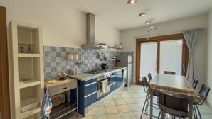 Cucina con piano cottura, lavello e zona pranzo con sedie.
