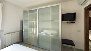 Una camera da letto con un letto, un armadio con porta scorrevole in vetro, un tavolino e una TV a parete.