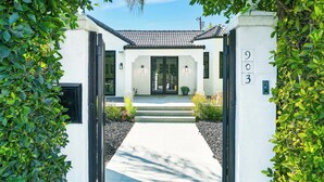 A modern building entrance with a white facade, black-framed doors, and a number '903' on the right.
