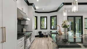 A modern kitchen with white cabinetry, a black countertop, and a glass island.