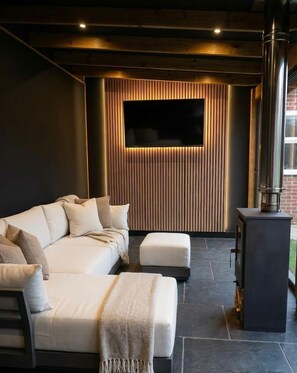 A modern living room with a sofa, ottoman, and a fireplace. - Sun Set House with Hot Tub (Witchford)