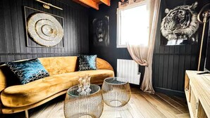 A cozy room with a wooden ceiling, a sofa with patterned cushions, and a tiger painting on the wall.