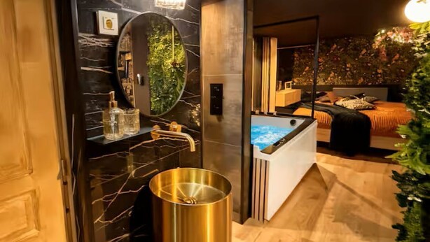 A modern bathroom with a marble vanity, a large mirror, and a gold-colored sink.