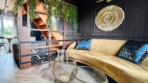 A modern interior with a wooden staircase, a curved sofa with patterned cushions, and a decorative wall hanging.