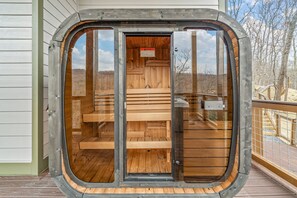 A sauna with wooden benches and a glass door, set on a wooden deck with a view of trees. - New & Lux Hottub, Sauna with Mt Views - Otter Run #4 (Gatlinburg)