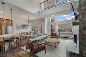 A spacious living area with a high ceiling, a dining table, sofas, and a fireplace. - New & Lux Hottub, Sauna with Mt Views - Otter Run #4 (Gatlinburg)