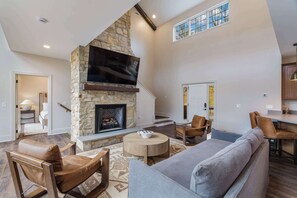 A spacious living room with a stone fireplace, a flat-screen TV, and comfortable seating. - Luxury Home w Hot Tub & Mt Views - Otter Run #2 (Gatlinburg)