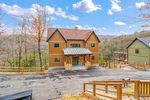A large wooden house with a metal roof, surrounded by a wooden fence and a gravel driveway. - Luxury Home w Hot Tub & Mt Views - Otter Run #2 (Gatlinburg)