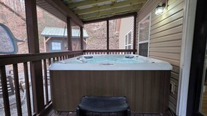 Eine Holzterrasse mit Whirlpool und Sitzbank.