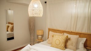 A bedroom with a bed, a bedside lamp, a hanging light fixture, and a mirror on the wall.