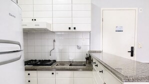 Eine kompakte Küche mit weißen Schränken, einem Gasherd, einem Backofen und einem Kühlschrank.