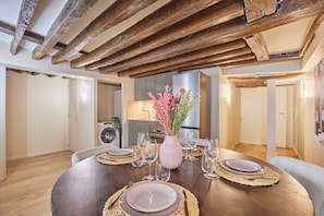 A dining area with a wooden table set for four, surrounded by chairs. A pink vase with flowers is on the table. - Amazing Apartment in Center of Paris (Paris)