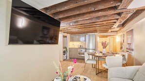 A modern kitchen with stainless steel appliances, a dining area with a round table and chairs, and a living room with a sofa. - Amazing Apartment in Center of Paris (Paris)