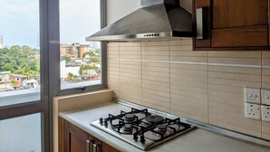 A kitchen with a gas stove, a window, and a view of buildings. - 3-bedroom apartment in peaceful Colombo with AC, gym and pool access (Colombo)