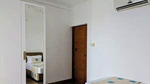 A hotel room with a bed, a wooden door, and an air conditioning unit on the wall. - 3-bedroom apartment in peaceful Colombo with AC, gym and pool access (Colombo)