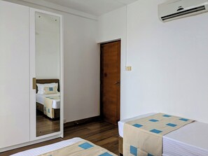 Ein Hotelzimmer mit einem Bett, einer Holztür und einer Klimaanlage an der Wand.