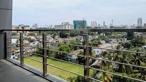 A balcony with a view of a cityscape, including buildings and greenery. - 3-bedroom apartment in peaceful Colombo with AC, gym and pool access (Colombo)