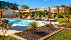 Un jardin avec une piscine, des chaises longues et une pergola.