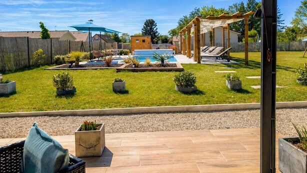 Un jardin avec une piscine, une pergola et un espace patio couvert.