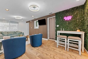 Ein modernes Wohnzimmer mit grüner Wand, Flachbildfernseher und Neonreklame.