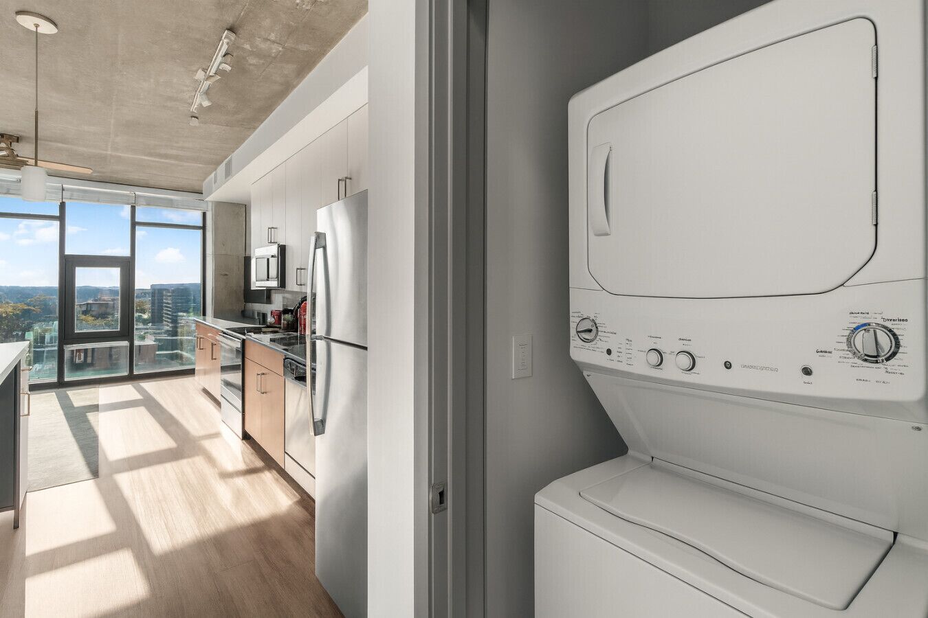 A modern kitchen with stainless steel appliances, a large window, and a view of the city.