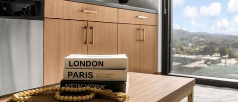 A modern kitchen with wooden cabinets, a wooden table, and a view of a cityscape through a large window.