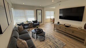 A modern living room with a sofa, coffee table, TV, and a dining area with chairs. - Contemporary 2 Bedroom 2 Bath in Beautiful Neighborhood (Los Angeles)