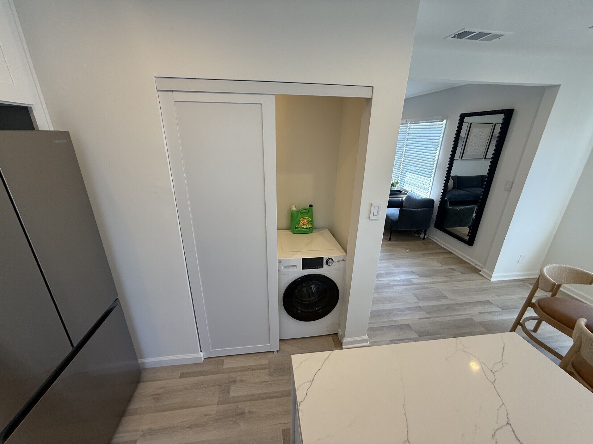 A compact kitchen with a washing machine, a dining table, and a refrigerator.