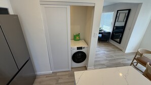 A compact kitchen with a washing machine, a dining table, and a refrigerator. - Contemporary 2 Bedroom 2 Bath in Beautiful Neighborhood (Los Angeles)