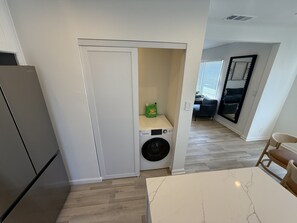 Eine kleine Küche mit Waschmaschine, Esstisch und Kühlschrank.