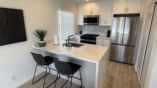 A modern kitchen with a marble island, stainless steel appliances, and black bar stools. - Contemporary 2 Bedroom 2 Bath in Beautiful Neighborhood (Los Angeles)