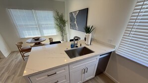 A modern kitchen with a marble countertop, white cabinetry, and a built-in dishwasher. - Contemporary 2 Bedroom 2 Bath in Beautiful Neighborhood (Los Angeles)