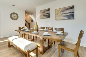 A dining area with a wooden table set for six, surrounded by chairs, a bench, and a vase with white feathers. - 15 Min to Disney: Resort Amenities, Pool! (Kissimmee)