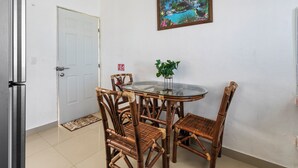 A dining area with a glass-top table, four bamboo chairs, a potted plant, and a framed picture on the wall. - Luna de Plata (Playa del Carmen)