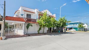 A two-story building with a red-tiled roof, a gated entrance, and a small tree in front. - Luna de Plata (Playa del Carmen)