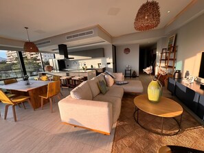 A modern living room with a sofa, coffee table, and dining area. - Oceanfront Bucerias Escape | Huge Balcony & Panoramic Views 🌊 (Bucerías)