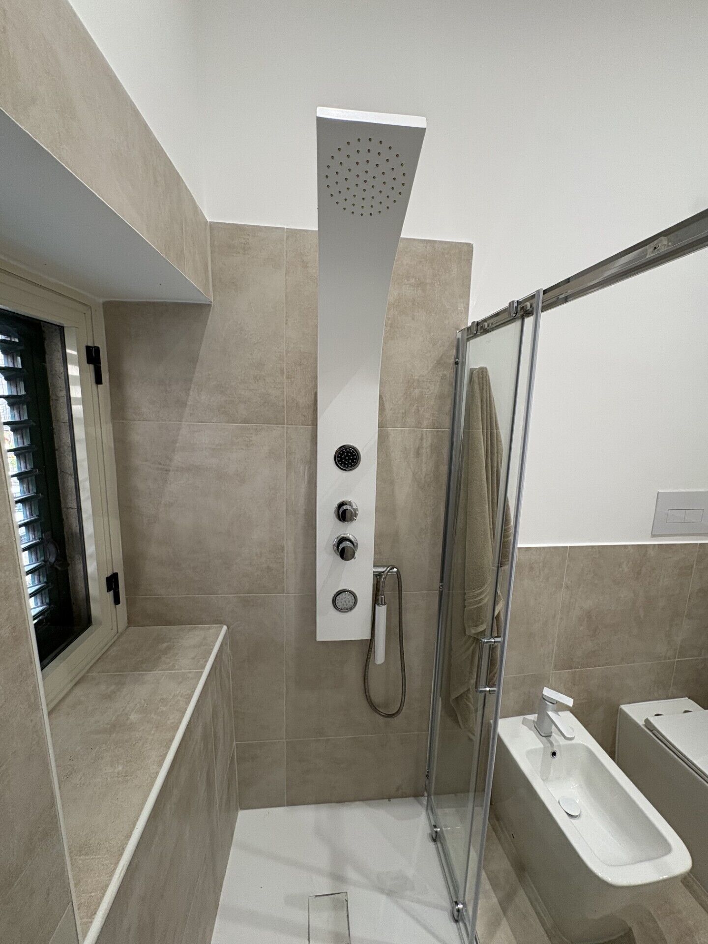 A modern shower with a rain showerhead, a handheld showerhead, and a handheld shower attachment.