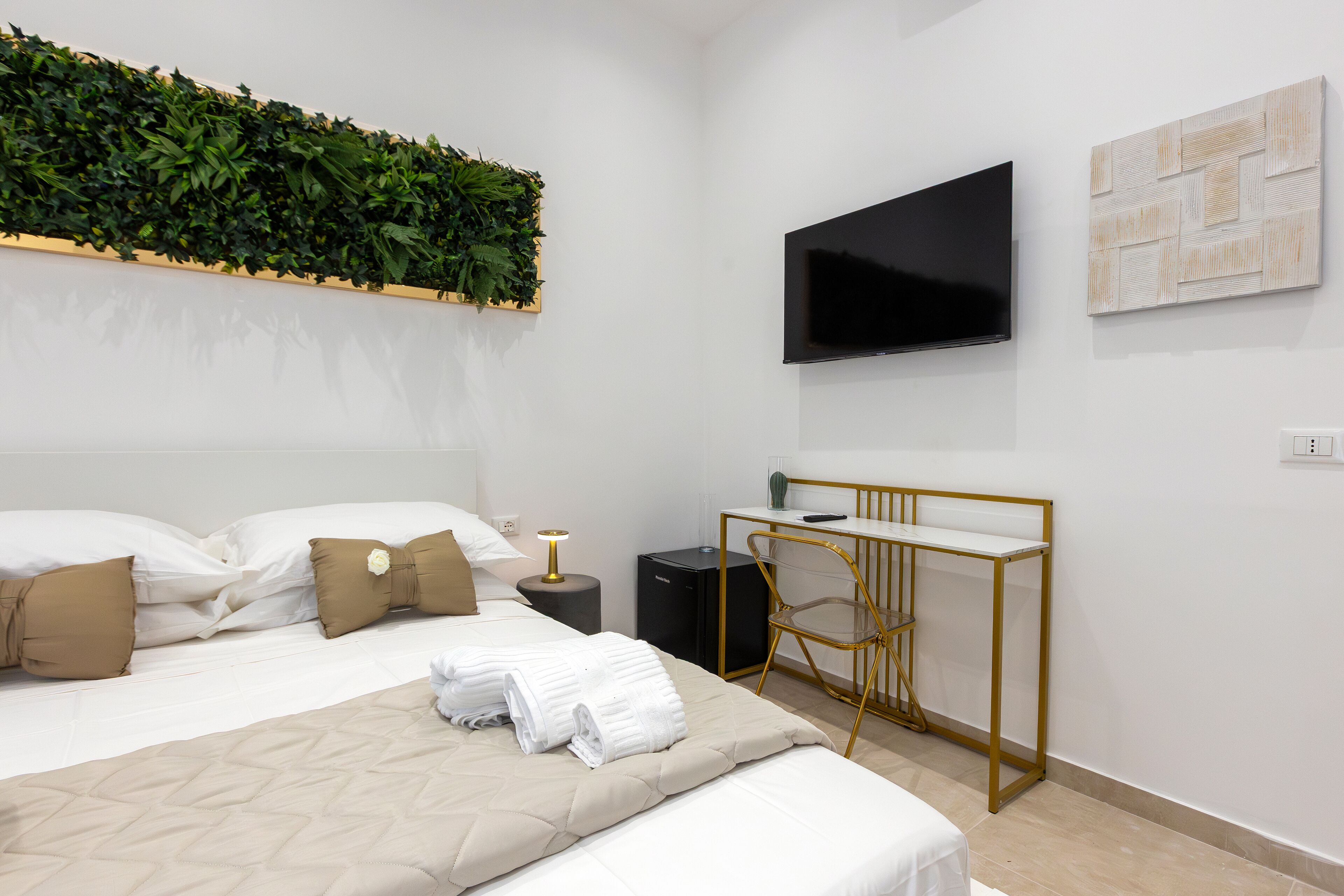 Una habitación de hotel moderna con una cama, un escritorio, un televisor y un adorno de pared verde.